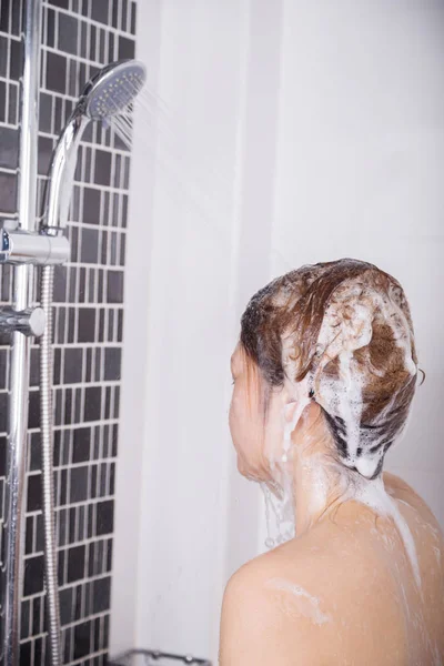 Mulher lavar a cabeça e o cabelo no chuveiro por shampoo — Fotografia de Stock