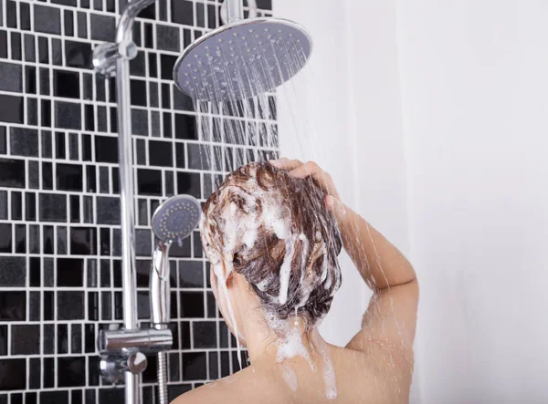 Frau wäscht Kopf und Haare in der Regendusche mit Shampoo, hinten — Stockfoto