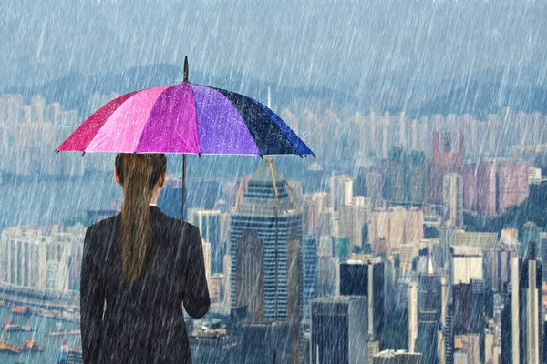 Mujer de negocios sosteniendo paraguas multicolor con lluvia — Foto de Stock
