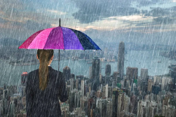 Mujer de negocios sosteniendo paraguas multicolor con lluvia — Foto de Stock