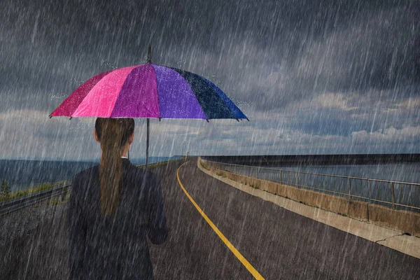 Mujer de negocios sosteniendo paraguas multicolor con lluvia — Foto de Stock