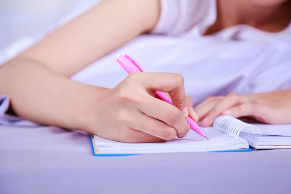 Close-up van de hand van vrouw schrijven van een boek op bed — Stockfoto