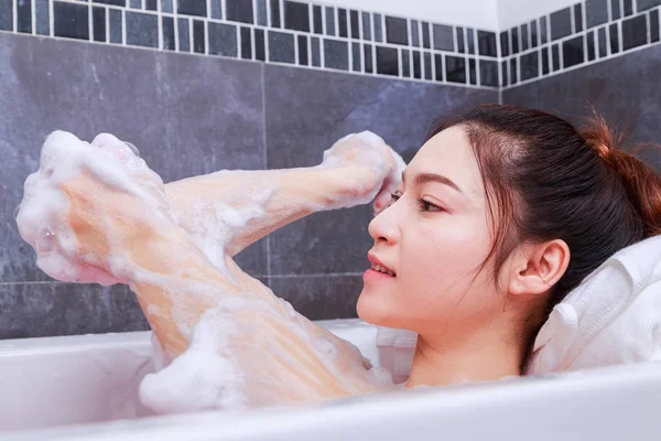 Frau wäscht Ellenbogen mit Schwamm in Badewanne im Bad — Stockfoto