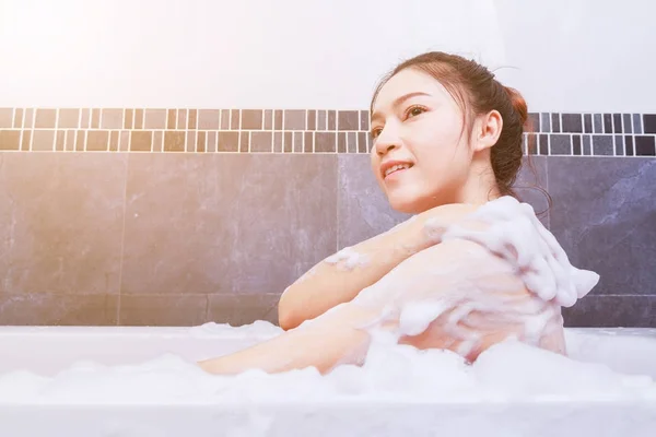 Femme se lave le dos dans la baignoire dans la salle de bain — Photo