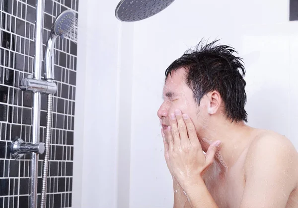 Człowieka są biorąc prysznic i mycia twarzy w łazience — Zdjęcie stockowe