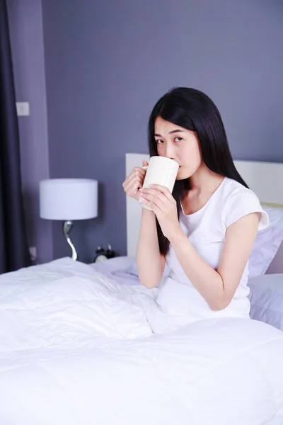 Wanita di tempat tidur dengan secangkir kopi di kamar tidur — Stok Foto
