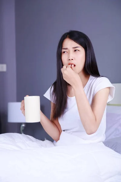 Woman taking pills and drink of water on bed in bedroom — Stock Photo, Image