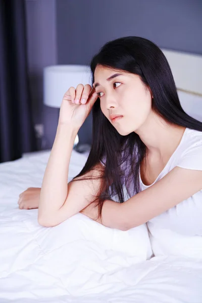 Worried woman thinking on bed in bedroom — Stock Photo, Image