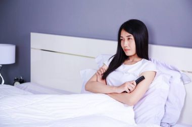 Uzaktan kumandalı yatak yatak odasında TV izlerken kadın