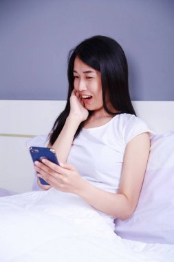 mutlu kadın yatakta yatak odasında elinde bir telefon kullanma