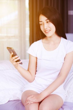 mutlu kadın yatakta yatak odasında elinde bir telefon kullanma