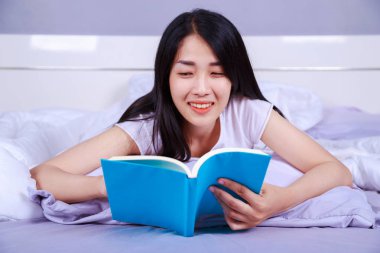 kadın evde yatak odasında yatağın üzerine bir kitap okuma