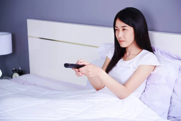 Femme regardant la télévision avec télécommande sur le lit dans la chambre — Photo