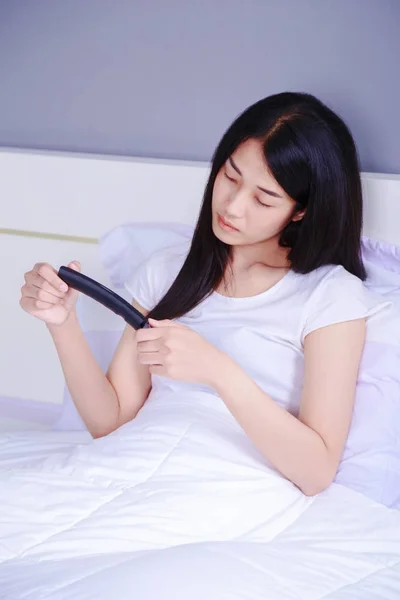 Woman watching tv with remote on bed in bedroom — Stock Photo, Image