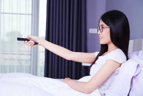 Femme regardant la télévision avec télécommande sur le lit dans la chambre — Photo