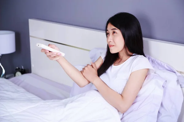 Mulher sentindo frio e mão pressione condicionador de ar remoto na cama — Fotografia de Stock