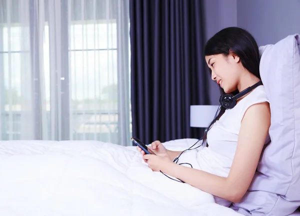 Femme utilisant un téléphone dans sa main sur le lit dans la chambre — Photo