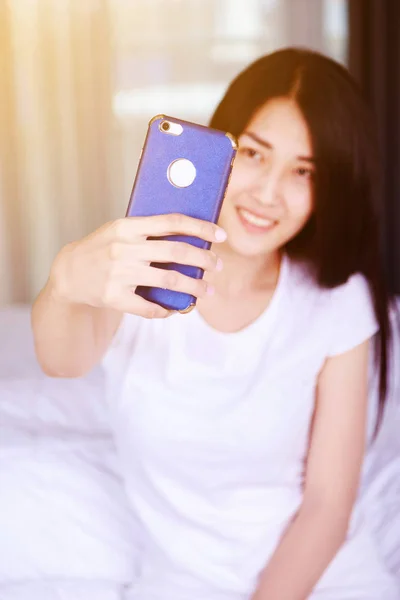 Donna che prende selfie sul letto in camera da letto — Foto Stock