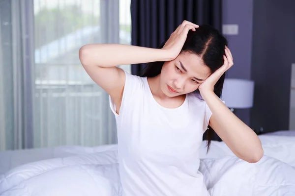 Woman with headache on bed in bedroom — Stock Photo, Image