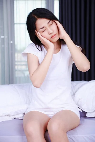 Woman with headache on bed in bedroom — Stock Photo, Image