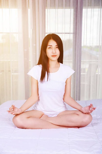 Mulher fazendo exercício de ioga na cama no quarto — Fotografia de Stock