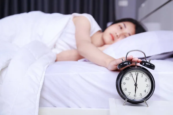 Kvinna som sover å säng och upphov till stänga av väckarklockan i b — Stockfoto