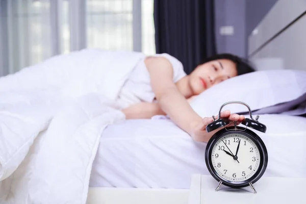 Kvinna som sover å säng och upphov till stänga av väckarklockan i b — Stockfoto