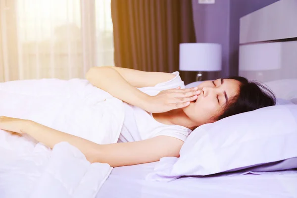 Mujer bostezando en la cama en el dormitorio — Foto de Stock