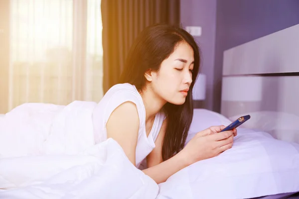 Femme utilisant un téléphone dans sa main sur le lit dans la chambre — Photo