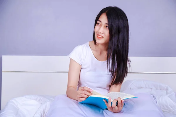 Mulher lendo um livro na cama no quarto em casa — Fotografia de Stock