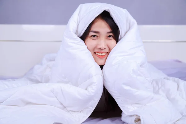 Wanita bahagia bersembunyi di bawah selimut di tempat tidur di kamar tidur — Stok Foto