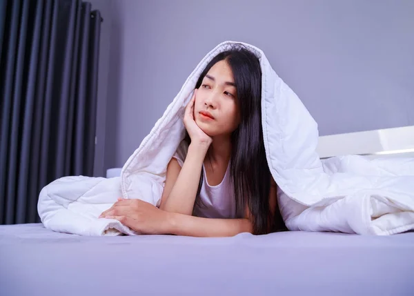 Wanita bahagia bersembunyi di bawah selimut di tempat tidur di kamar tidur — Stok Foto