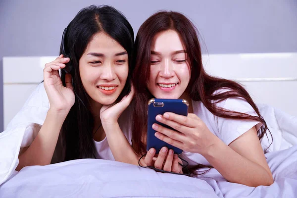 Deux femmes utilisant un téléphone dans sa main sur le lit dans la chambre — Photo