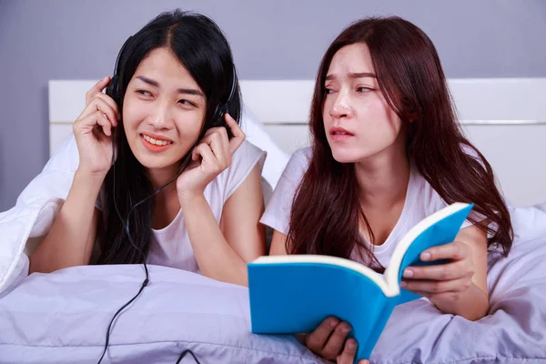 책을 읽고 하 고 스마트 전화를 사용 하 여 침실에서 침대에 두 여자 — 스톡 사진