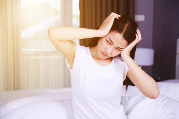 Vrouw met hoofdpijn op bed in de slaapkamer Stockfoto