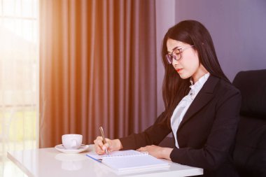 iş kadını masada oturan ve üzerinde Not bir not yazıyor