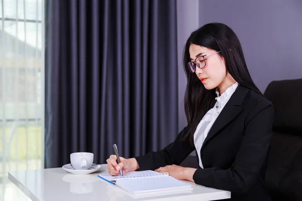 Business woman sitting at the desk and writes a note on the note — Stock Photo, Image