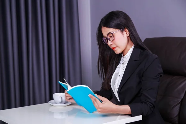 Zakenvrouw zitten aan de balie en het lezen van een boek — Stockfoto