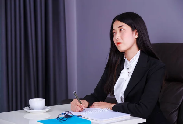 Business woman thinking and writes a note on the notebook — Stock Photo, Image