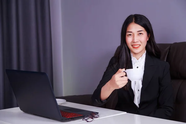 Щаслива ділова жінка працює на ноутбуці і п'є c — стокове фото