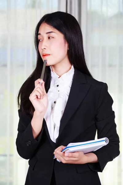 Business kvinna tänka tanken och hålla en penna och anteckningsbok — Stockfoto