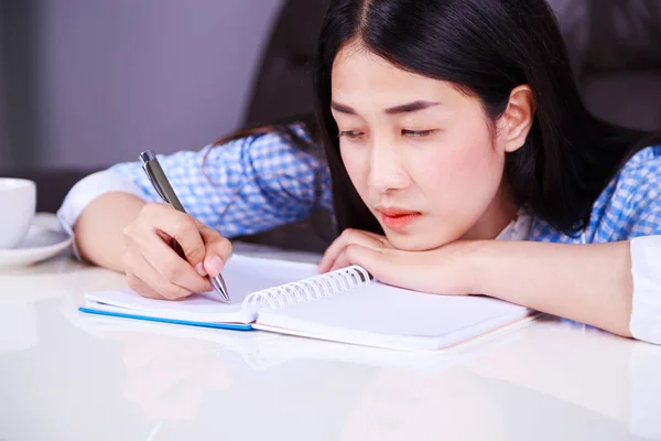 Gestresste Geschäftsfrau sitzt an ihrem Schreibtisch und schreibt einen Zettel an — Stockfoto