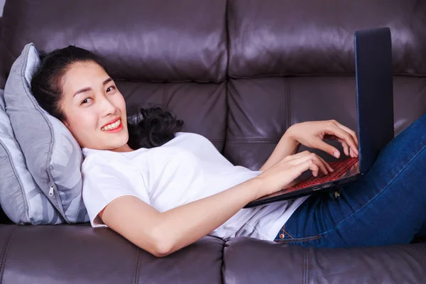 Jeune femme à l'aide d'un ordinateur portable sur canapé dans le salon à ho — Photo