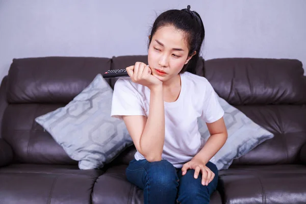 Woman with tv remote control on sofa at home — Stock Photo, Image