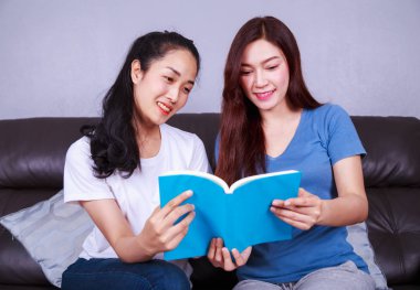 iki kadın evde oturma odasında kanepede kitap okuma
