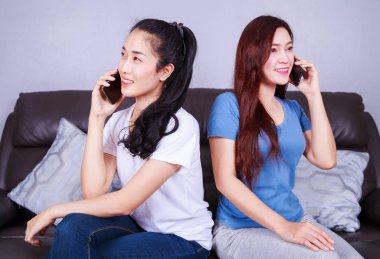 iki kadın evde oturma odasında kanepede cep telefonunda söz