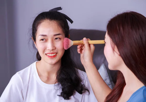 Mujer usando cepillo maquillaje en la cara su amigo — Foto de Stock