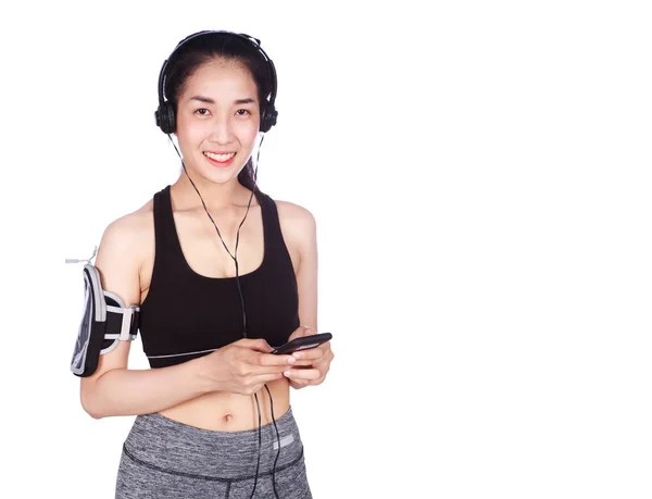 Fitness woman listening to music with earphones while standing a — Stock Photo, Image