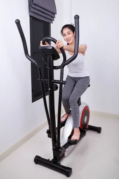 Sportieve vrouw doen oefeningen met elliptische trainer — Stockfoto