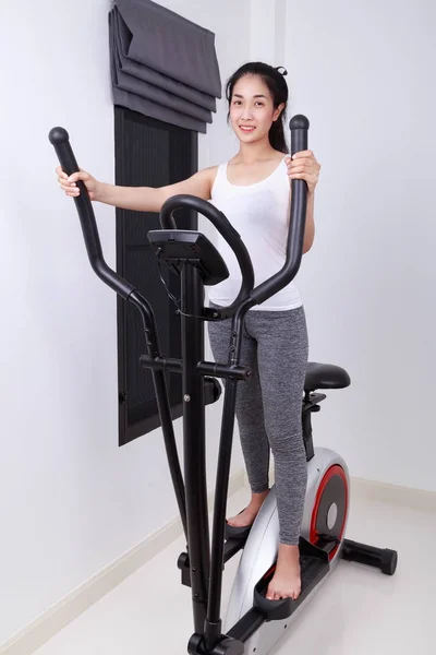 Sportieve vrouw doen oefeningen met elliptische trainer — Stockfoto